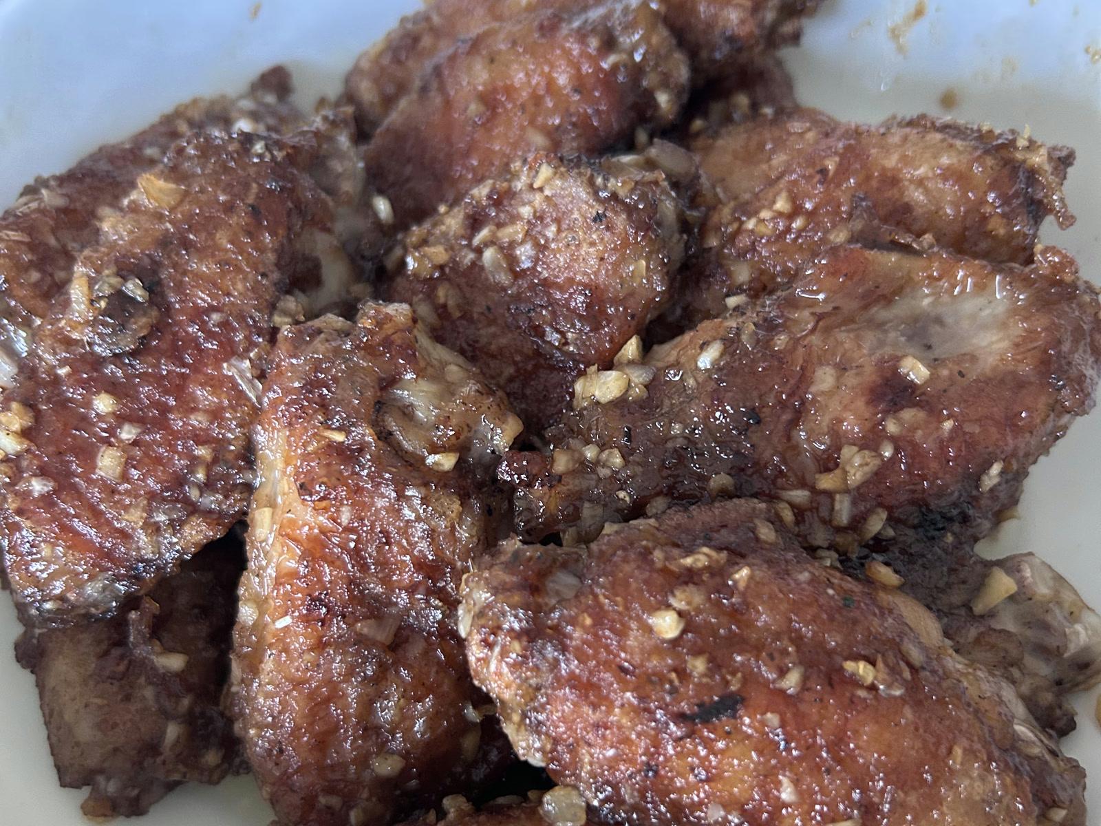 Air fryer chicken wings covered with a glossy caramelized garlic-soy glaze