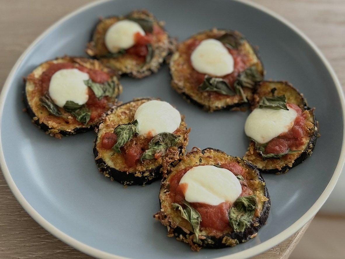 Breaded eggplant rounds topped with marinara, melted mozzarella, and basil