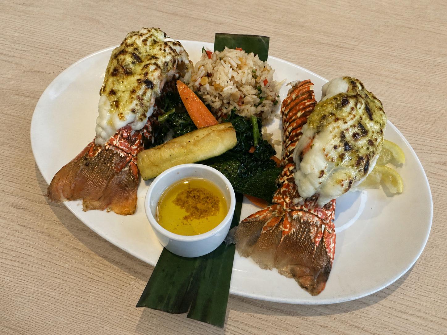 Baked lobster tails with basil garlic butter, herbed rice, roasted vegetables, and lemon butter
