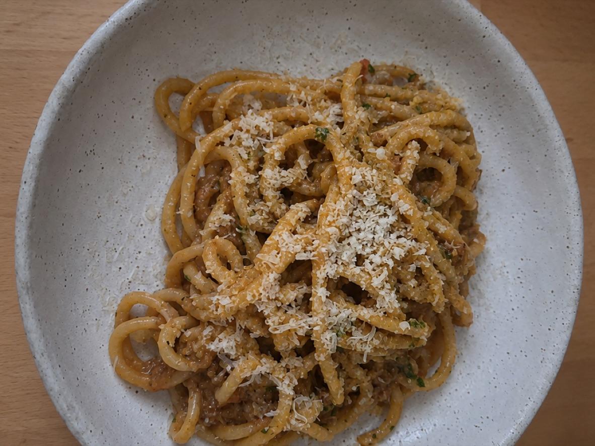 Bucatini coated in beef-and-pork ragù and topped with grated cheese