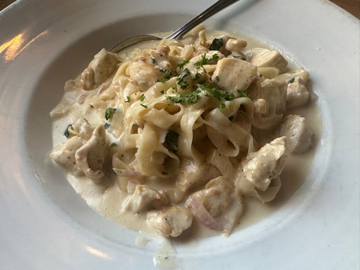 Chicken fettuccine Alfredo with wide noodles, grilled chicken, Parmesan cream sauce, and herbs