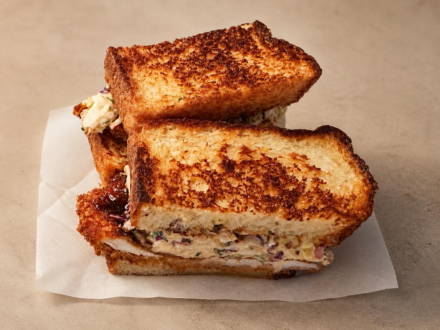 Crispy chicken katsu sandwich with spicy miso slaw and hoisin on white deli paper