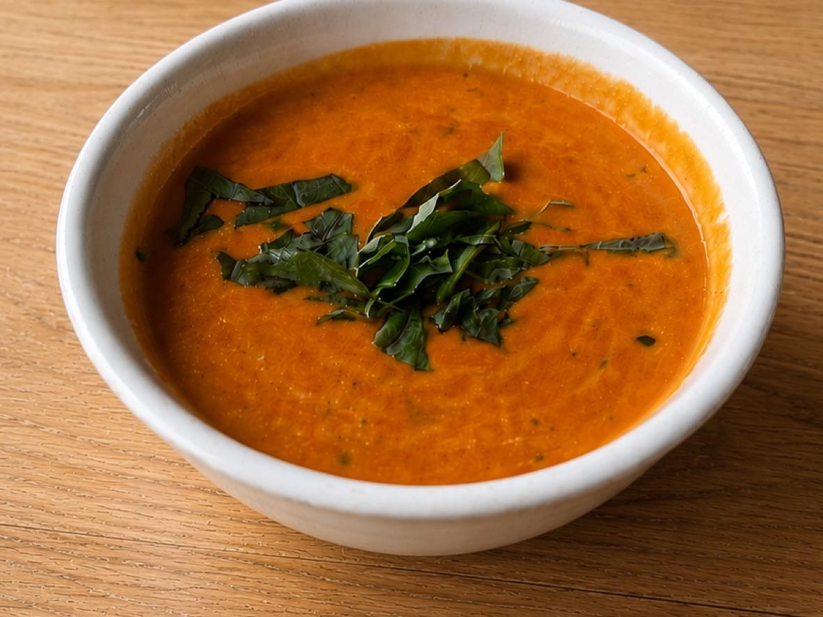 Creamy tomato basil soup topped with sliced basil in a white bowl