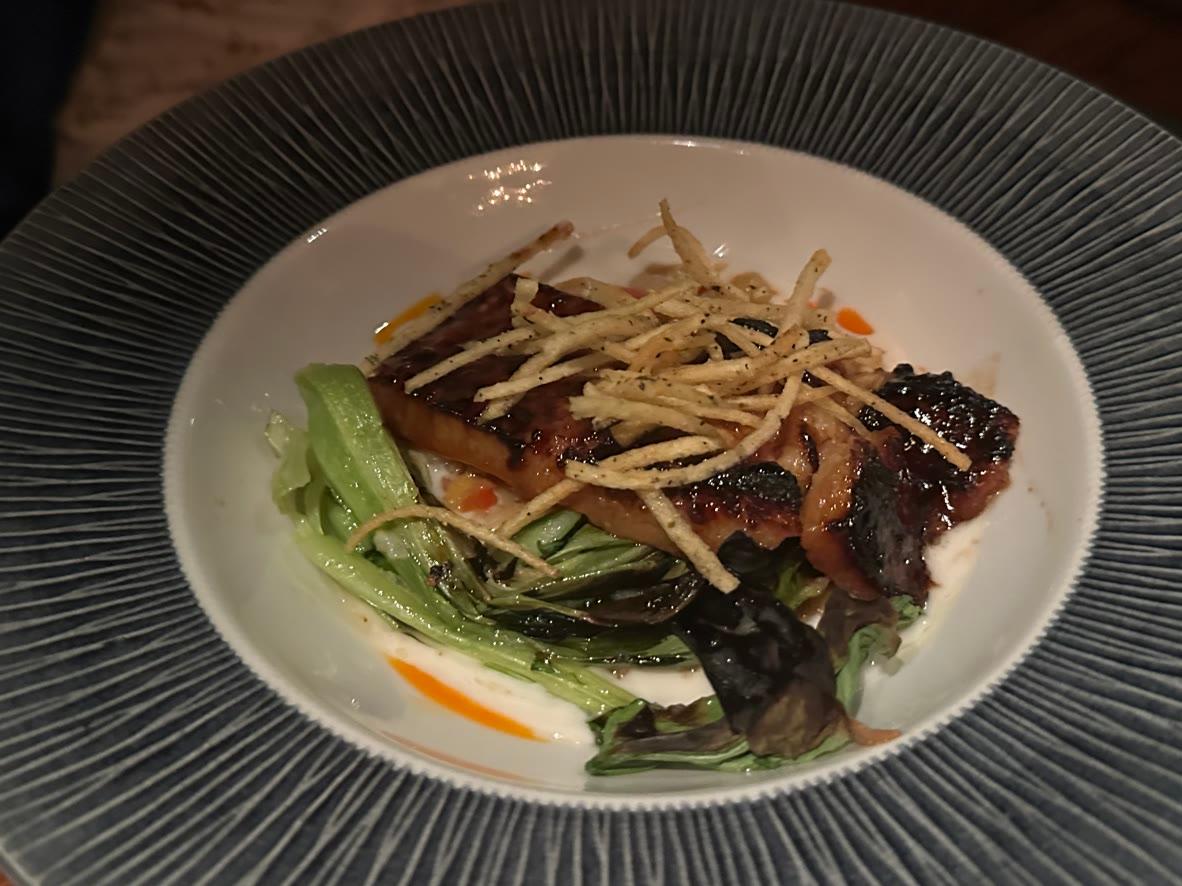 Crispy duck confit with bitter greens, orange vinaigrette, and shoestring potatoes