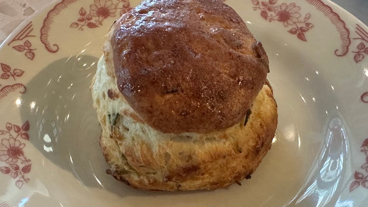 Tall round honey-lavender scone brushed with honey butter on a floral plate