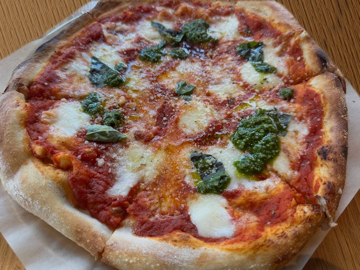 Margherita pizza with fresh mozzarella, tomato, basil leaves, and spoonfuls of basil oil