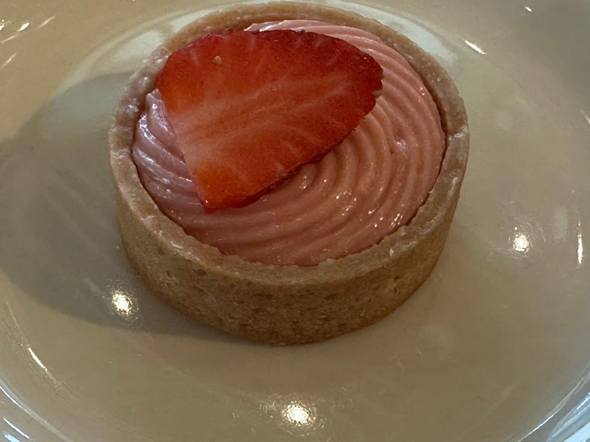 Mini strawberry cream tart with piped pink filling and a fresh strawberry slice
