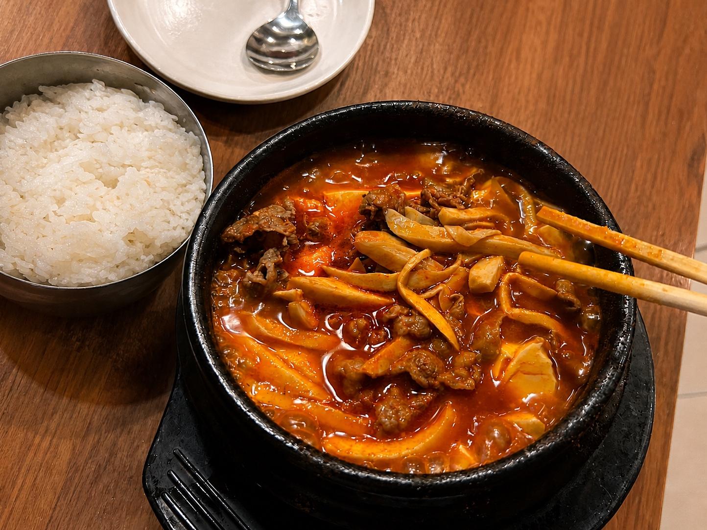 Mushroom sundubu jjigae with soft tofu, sliced beef, and mushrooms in a black stone bowl