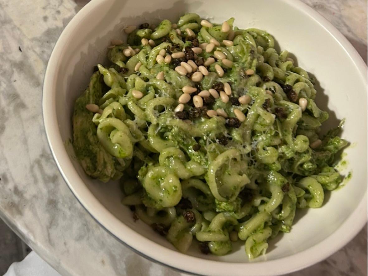 Curly pasta coated in basil pesto and topped with pine nuts and black pepper