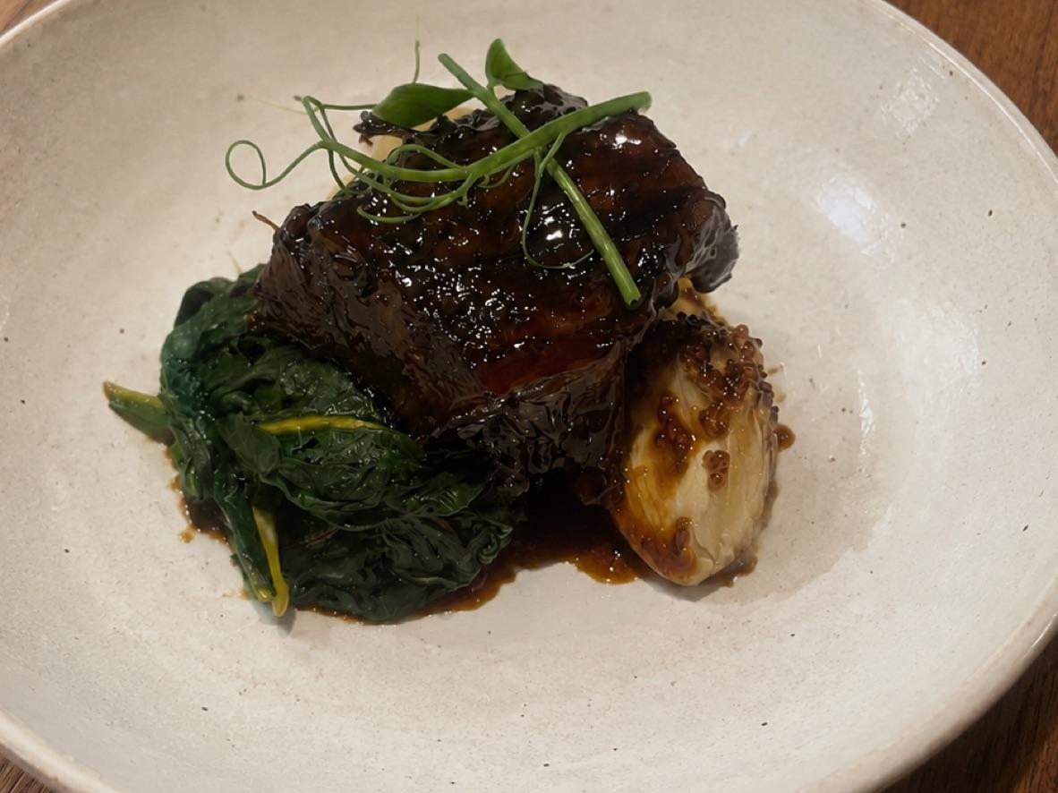 Red wine-braised short rib over mashed potatoes with garlicky greens and roasted shallot