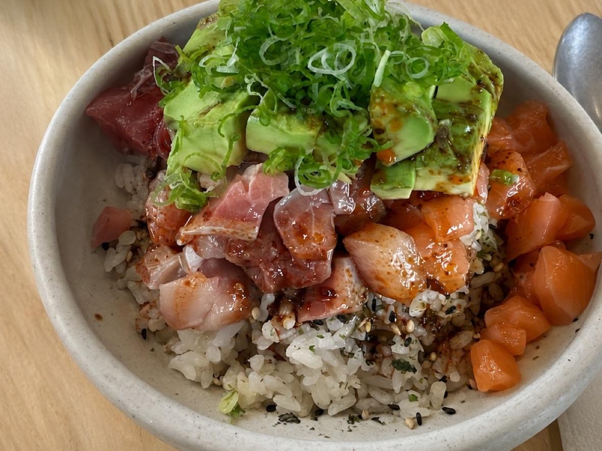 Spicy tuna and salmon poke bowl with avocado, scallions, and rice