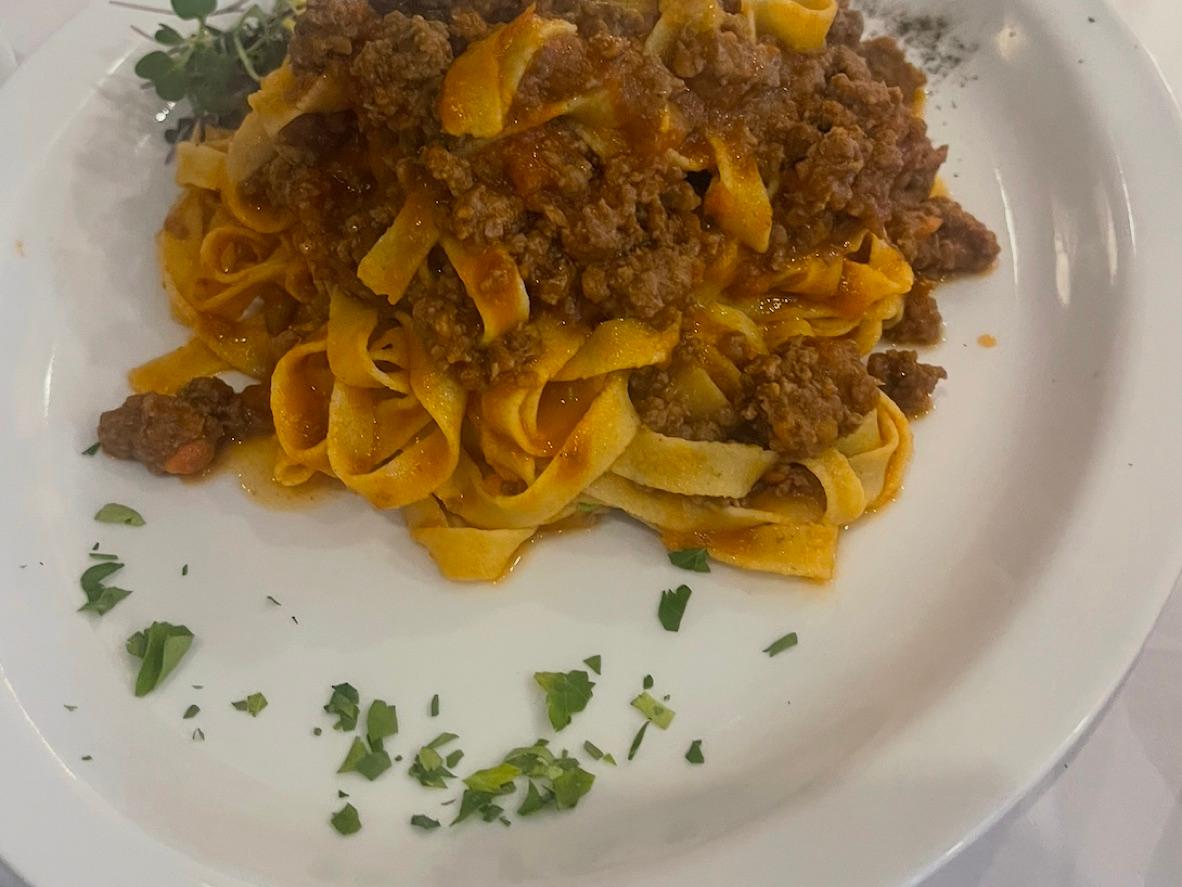 Tagliatelle topped with chunky meat ragù and chopped parsley
