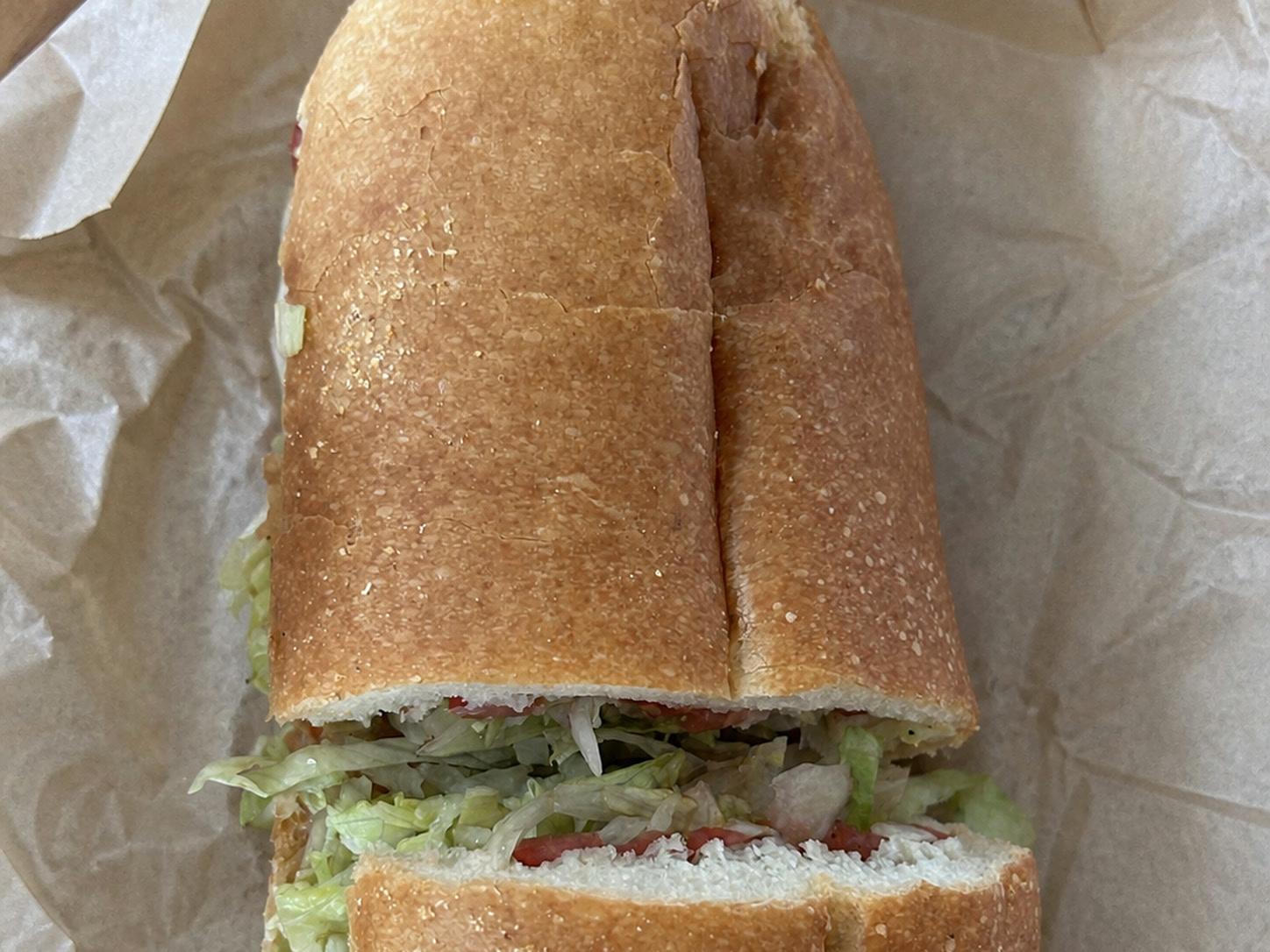 Turkey and provolone sub with shredded lettuce, tomato, onion, oil, and vinegar on parchment paper