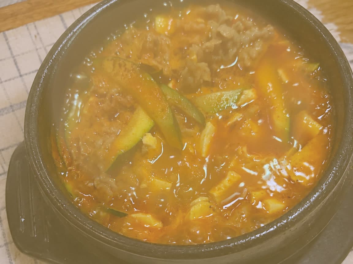 Beef sundubu jjigae with zucchini and soft tofu in a black stone bowl