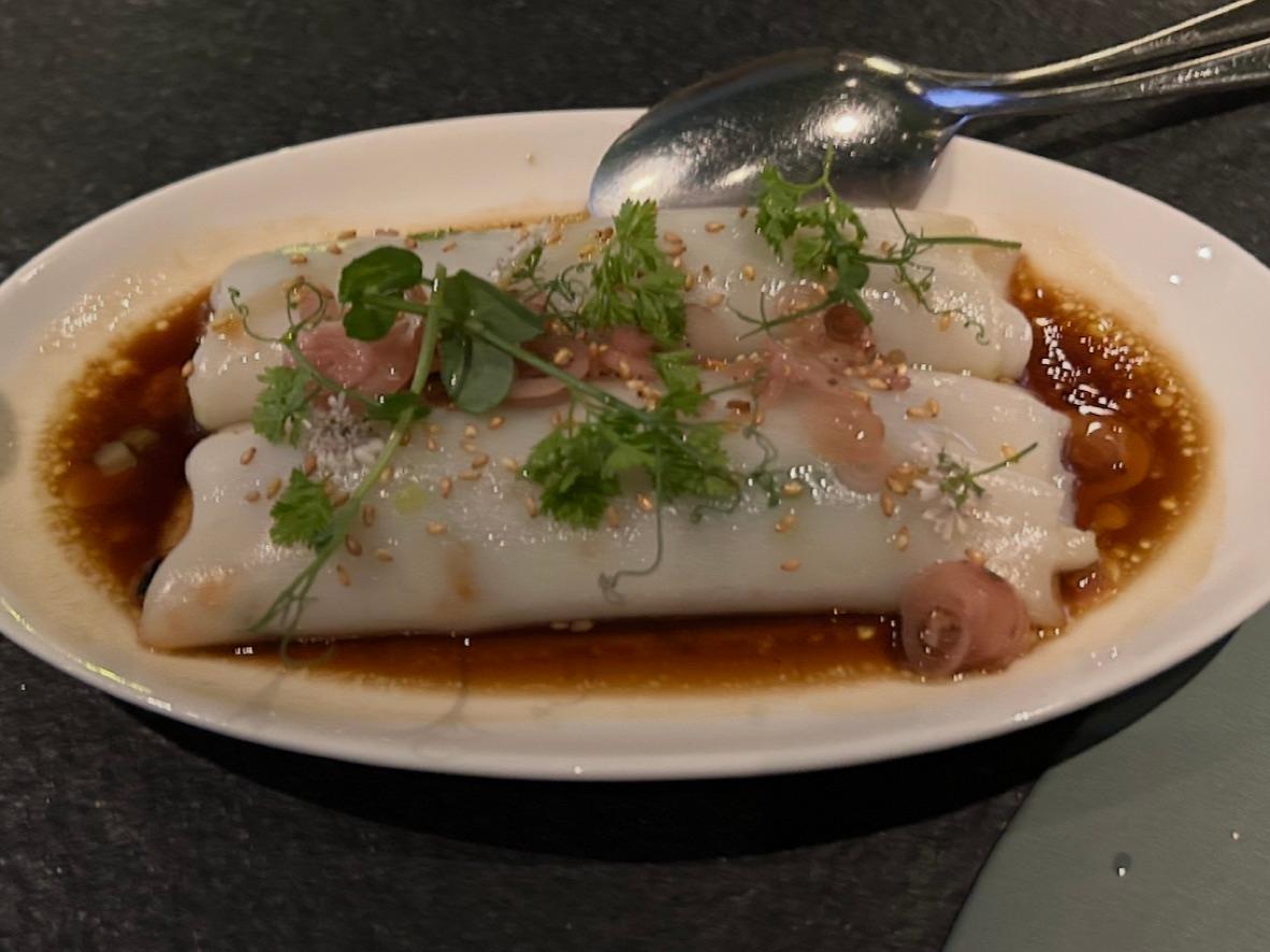 Char siu cheung fun rice rolls in soy sauce with sesame seeds and cilantro