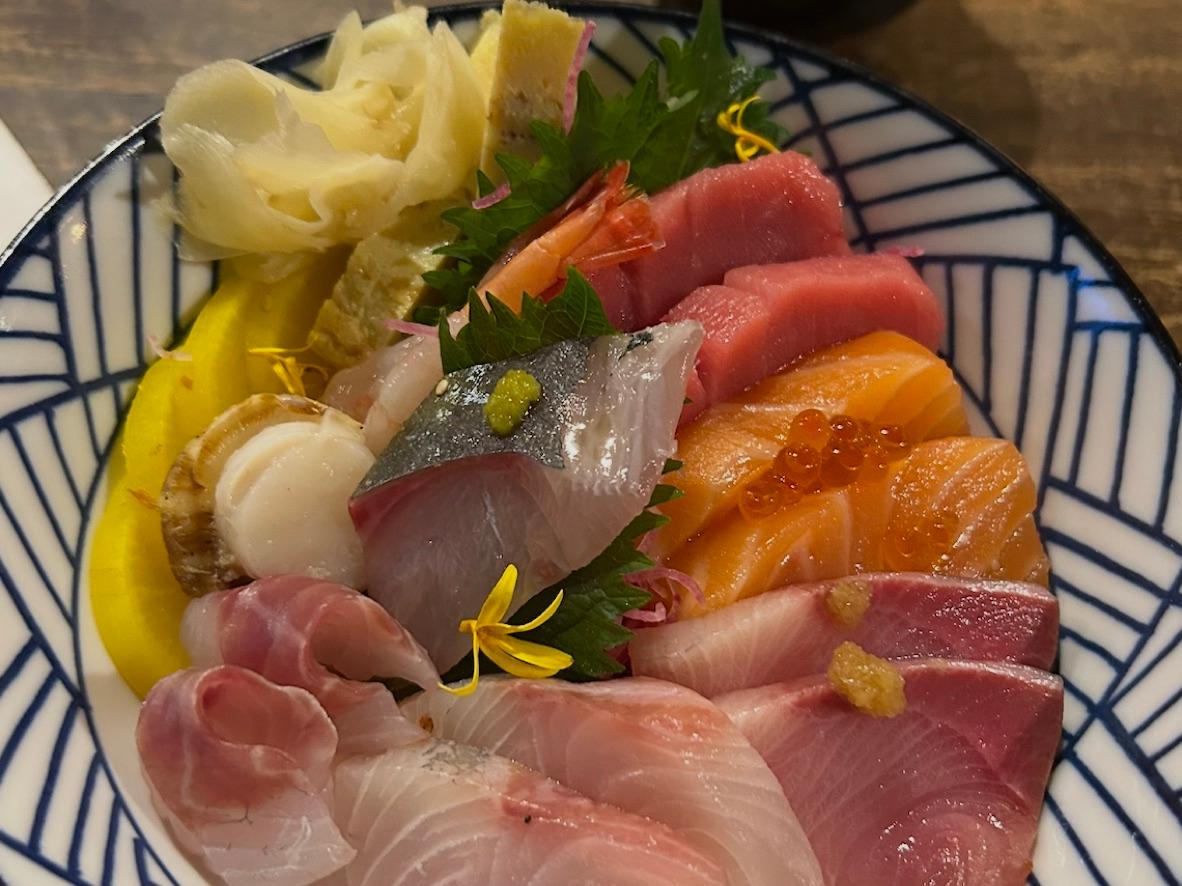 Chirashi sushi bowl with assorted sashimi, shrimp, tamago, and pickles over rice