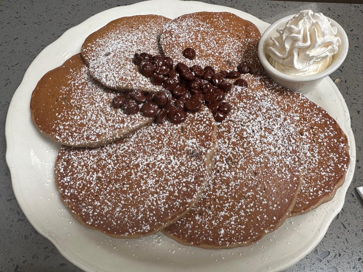 Chocolate chip pancakes dusted with powdered sugar and served with whipped cream