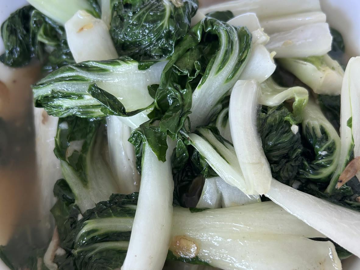 Garlic bok choy stir-fry with soft green leaves and pale tender stems in a light sauce
