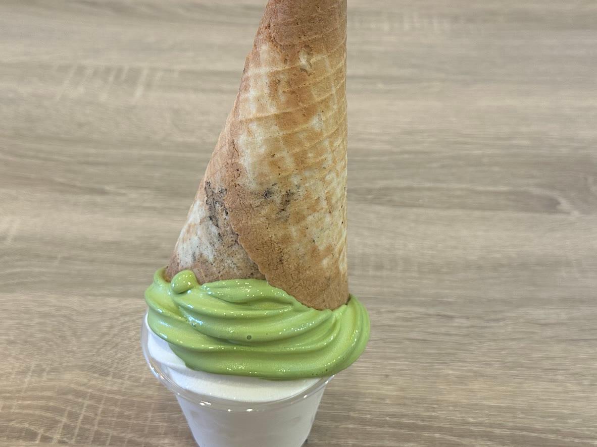 Homemade green matcha soft serve in a cup with an upside-down waffle cone