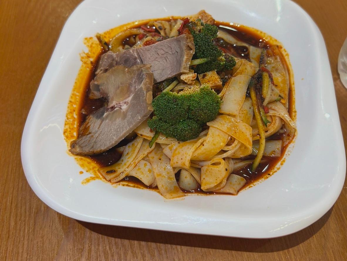 Wide liang pi noodles with sliced beef, broccoli, and spicy red chile sauce