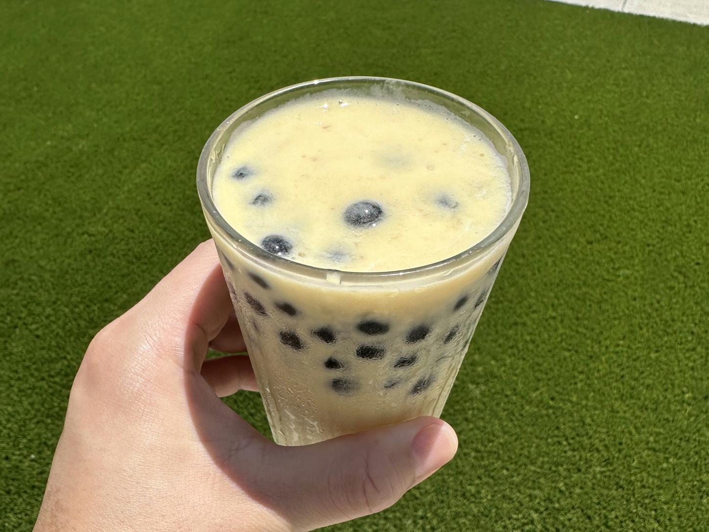 Creamy mango boba smoothie with black tapioca pearls in a clear glass