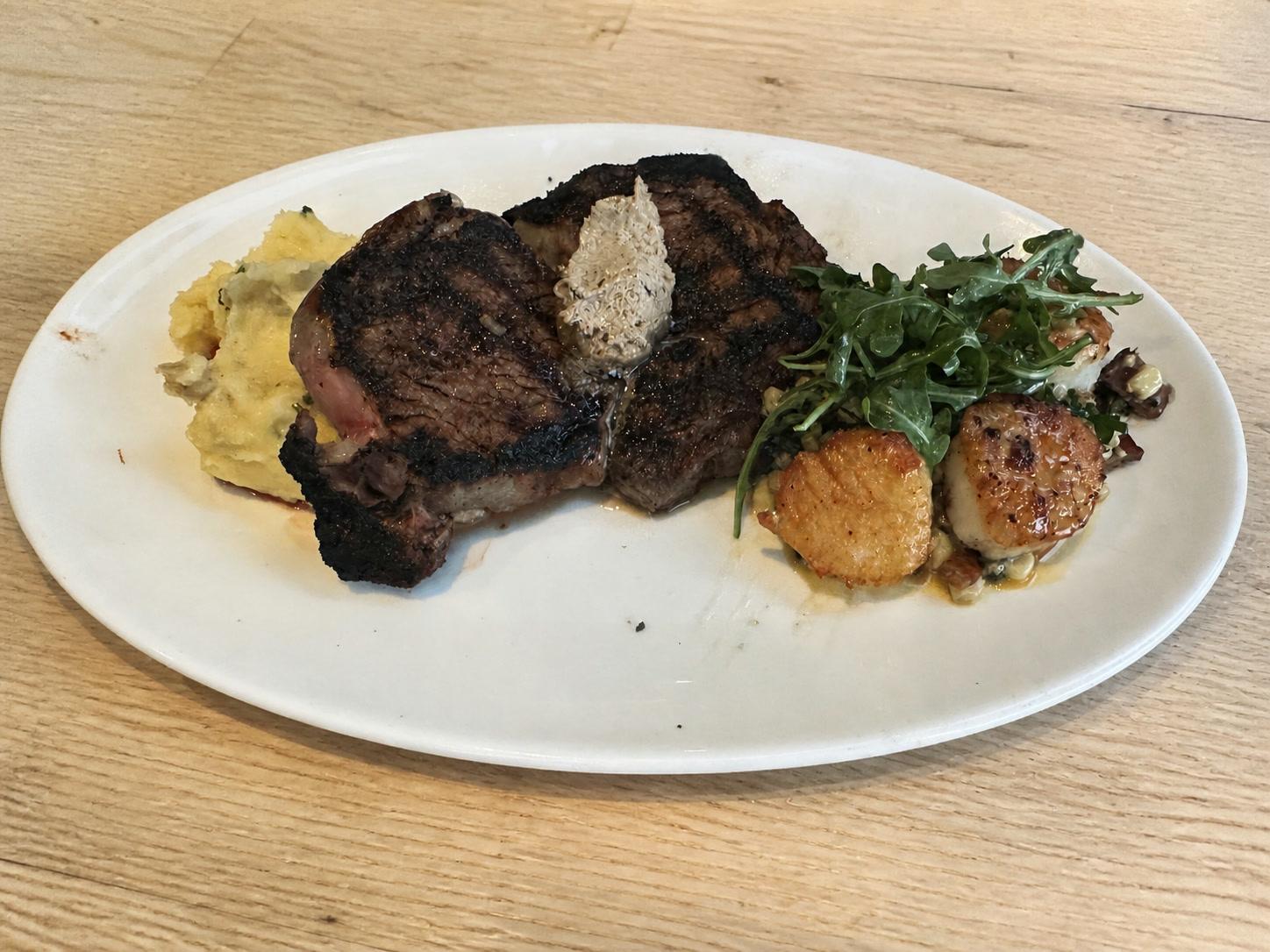 Pan-seared steak and scallops with garlic mashed potatoes, corn, arugula, and compound butter