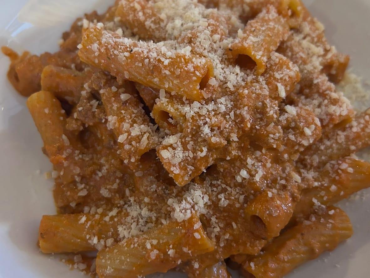 Rigatoni coated in Bolognese-style meat sauce and topped with grated Parmesan