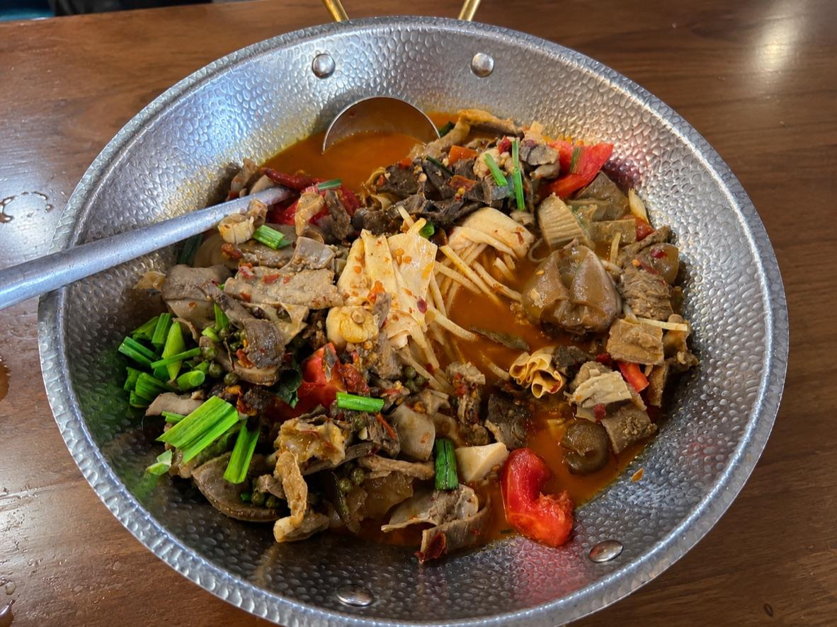 Spicy beef offal pot with tripe, tendon, cabbage, chiles, and scallions